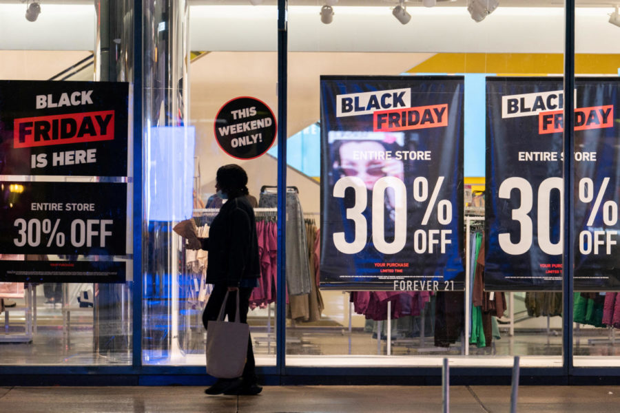 FILE PHOTO: A woman passes by signs advertising sales of Black Friday in the Manhattan borough of New York City, New York, U.S., November 26, 2021. REUTERS/Jeenah Moon/File Photo